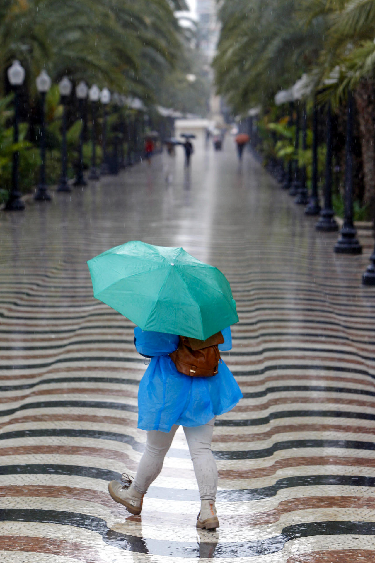 Una persona pasea bajo la lluvia por la explanada de Alicante. EFE/Morell
