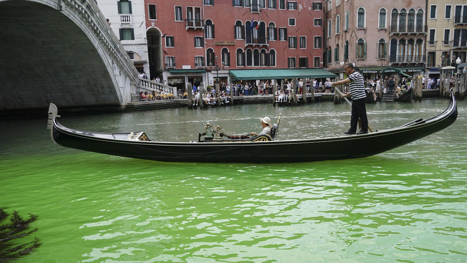A gondolier propels a gondola along a patch of phosphorescent green liquid seen on the Grand Canal near the Rialto Bridge, in Venice, Italy, 28 May 2023. EFE/EPA/ANDREA MEROLA