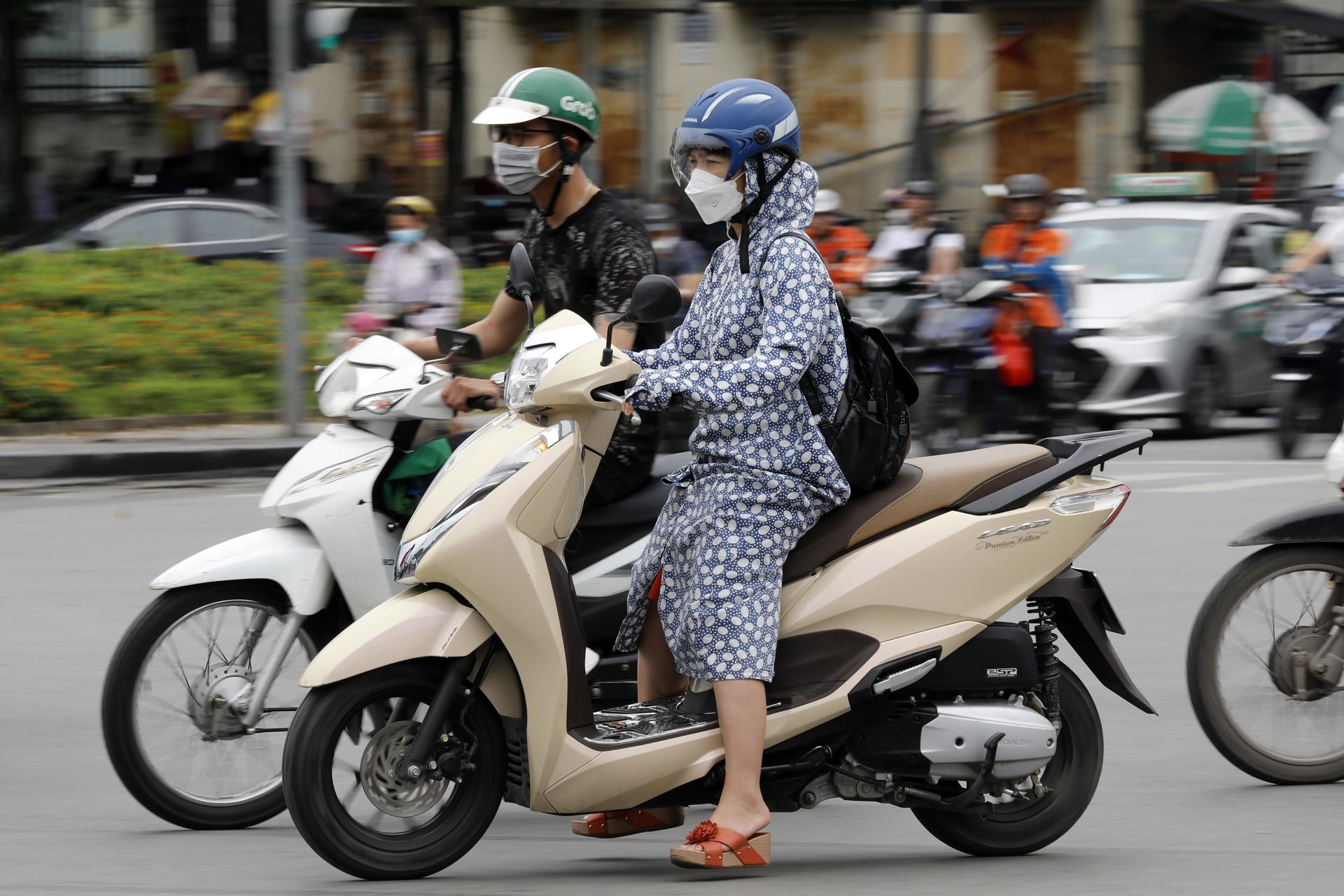 A woman wears long clothing to protect herself from the heat while riding a motorcycle along a street in Hanoi, Vietnam 08 May 2023. EFE-EPA/LUONG THAI LINH