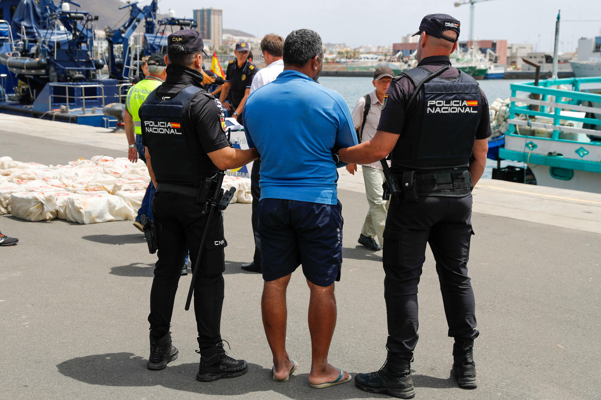 La Policía custodia en el puerto de Las Palmas de Gran Canaria a uno de los detenidos, el patrón del pesquero, mientras se descarga el alijo de 1.500 kilos de cocaína. EFE/Elvira Urquijo Á.