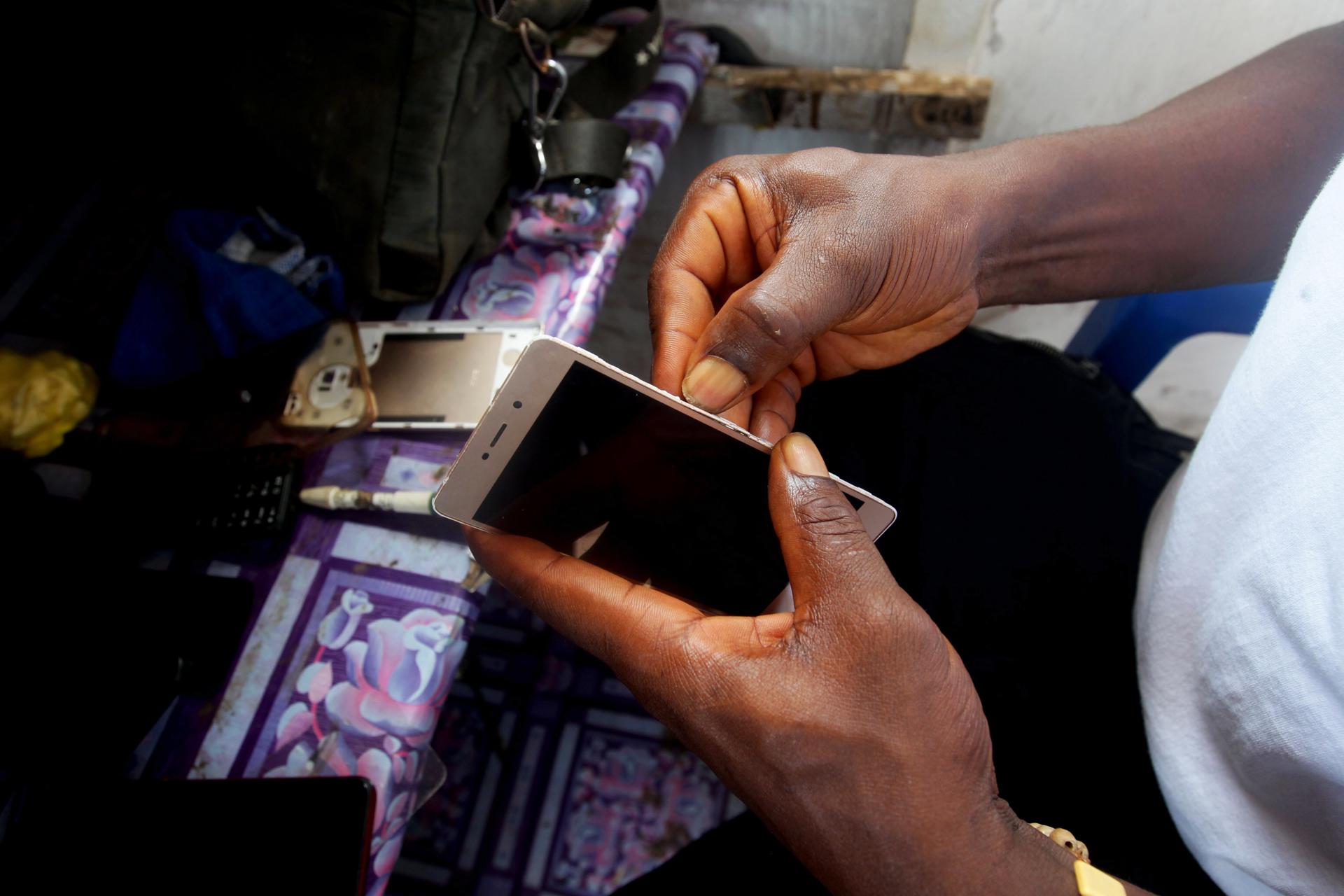 Un reparador de móviles trabajando en una calle de Monrovia (Liberia), en una imagen de archivo. Los móviles reacondicionados al alza