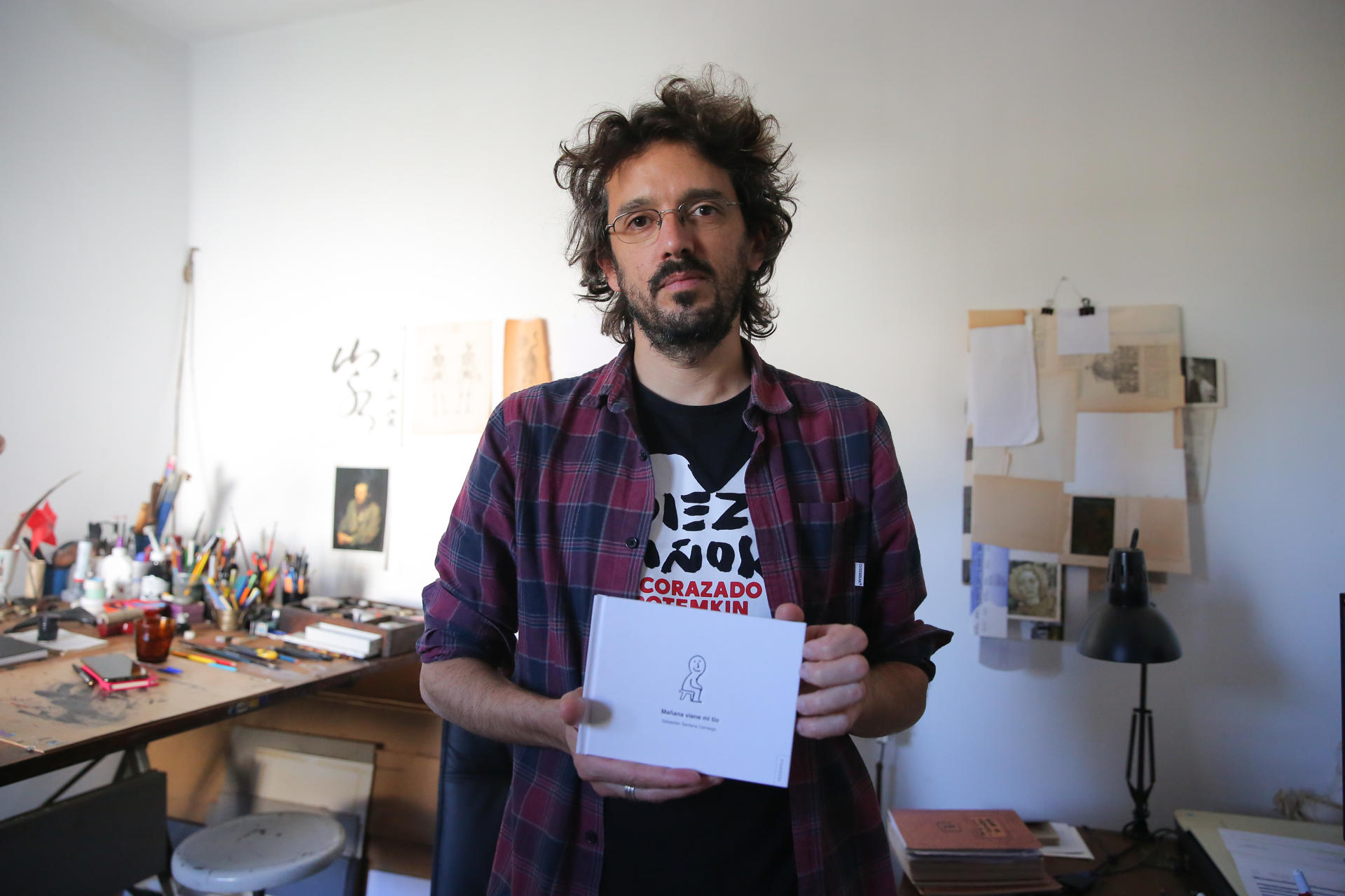 El ilustrador uruguayo Sebastián Santana posa con su libro "Mañana viene mi tío", el 17 de mayo de 2023, en Montevideo (Uruguay). EFE/Alejandro Prieto
