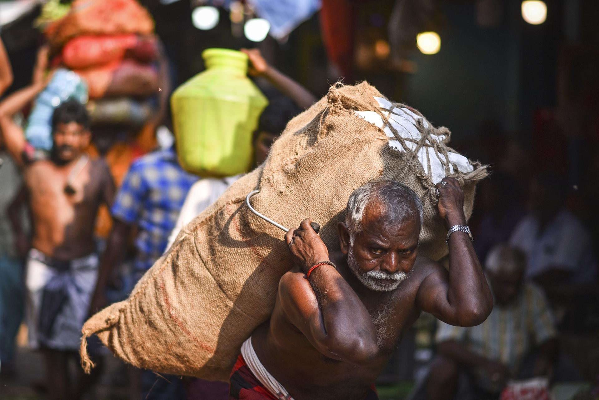 An Indian laborer carries a sack of vegetables at a market, in Chennai, India, 31 May 2023. EFE-EPA/IDREES MOHAMMED