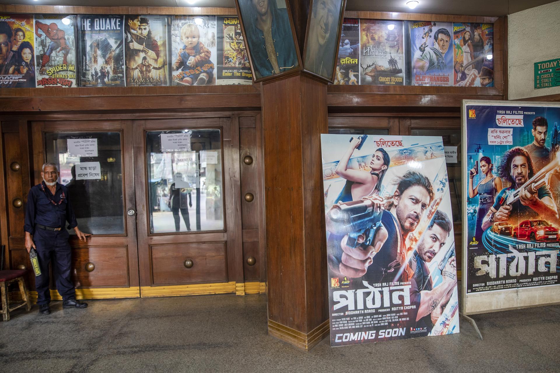 A Bangladeshi security guard stands next to posters of the Indian Hindi-language movie 'Pathaan' displayed at entrance of the Modhumita Cinema Hall in Dhaka, Bangladesh, 12 May 2023. EFE-EPA/MONIRUL ALAM