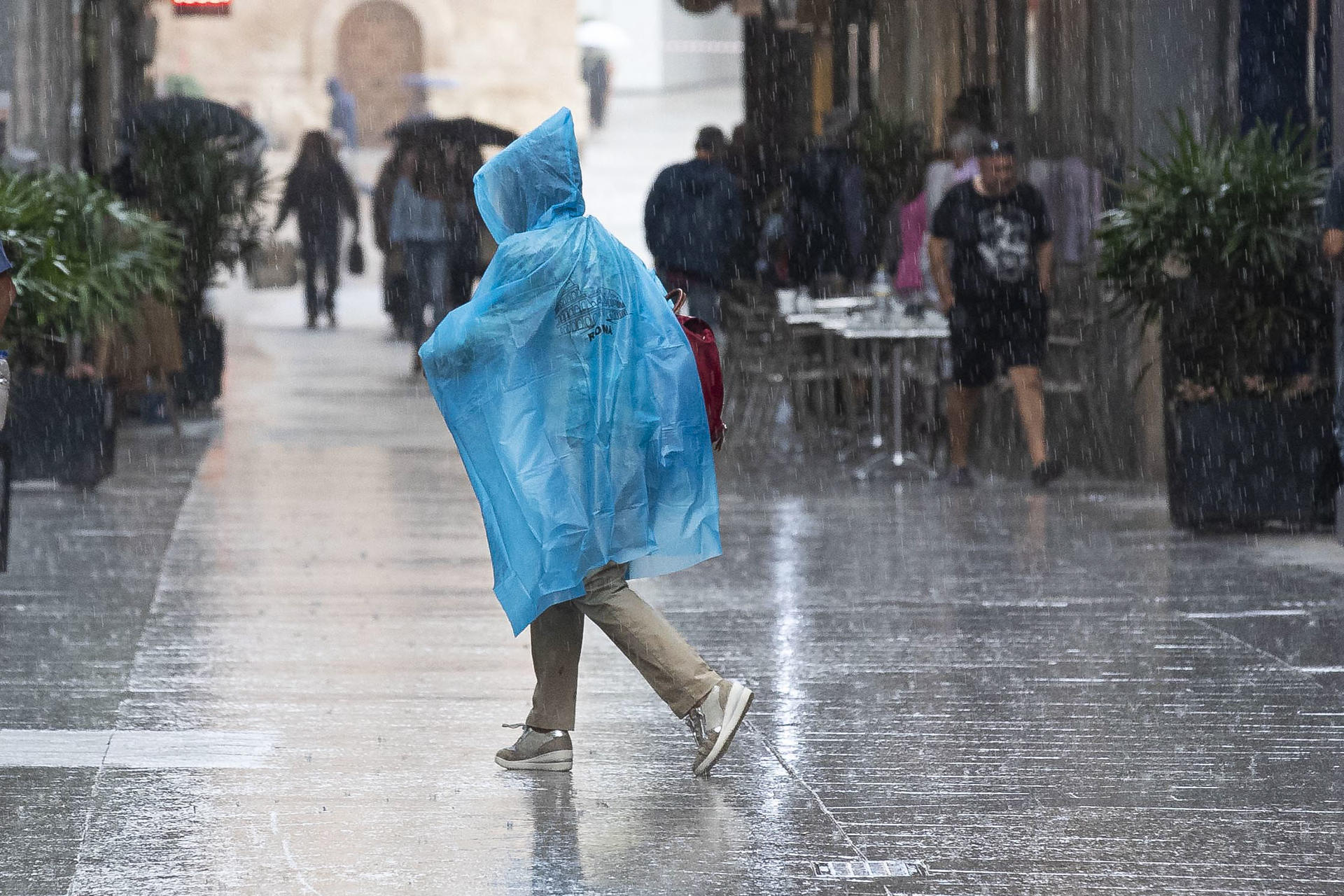 En la imagen de archivo, una mujer se protege de la lluvia con un chubasquero, en la calle Trapería de Murcia. EFE/Marcial Guillén