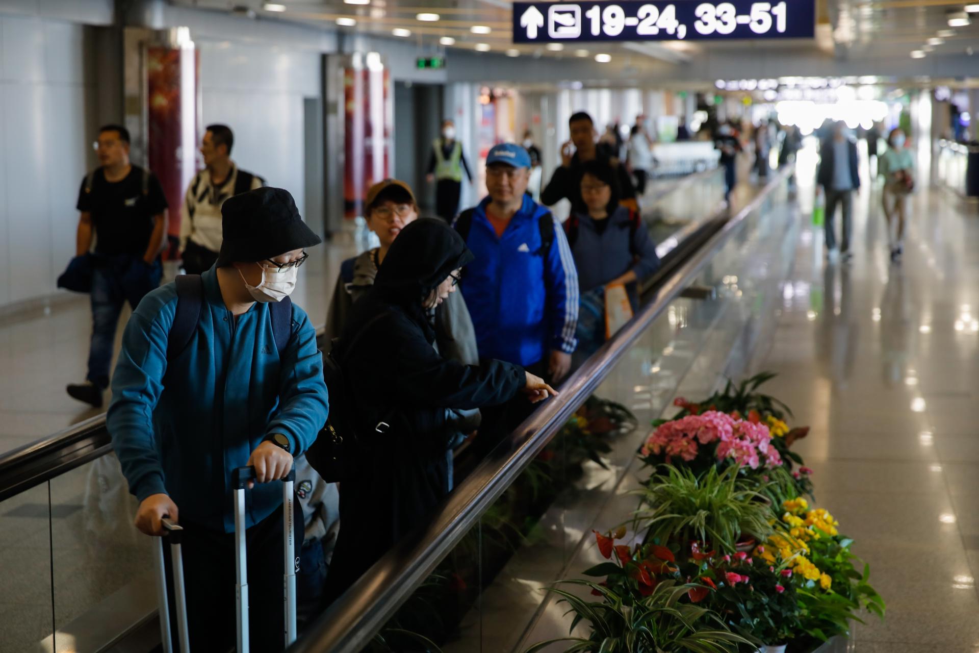 Passengers wearing face masks walk with their luggage at Beijing Capital International Airport in Beijing, China, 30 April 2023. EFE-EPA FILE/WU HAO