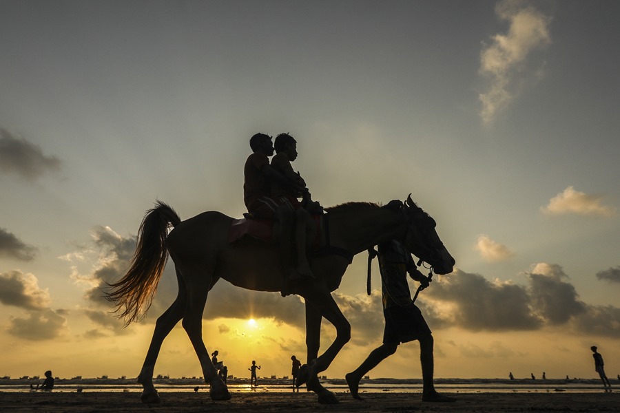 Dos personas montan a caballo durante el atardecer en la playa de Gorai, en Bombay. 