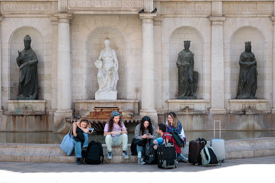Un grupo de turistas descansa con sus maletas junto a una fuente en el centro de Valencia. El tiempo del fin de semana trae bajada de temperaturas en Valencia
