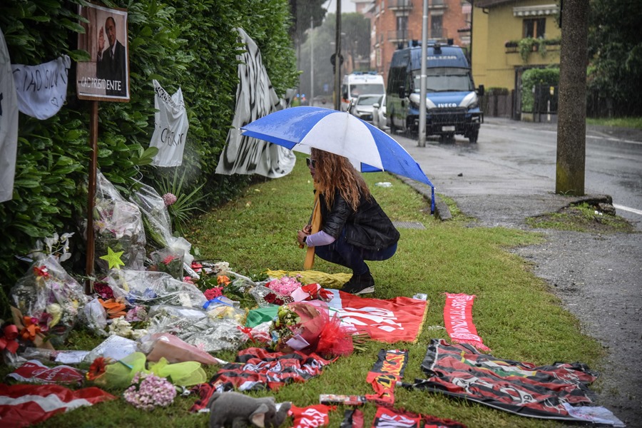 Una mujer junto a los homenajes y las flores colocados en la entrada de Villa San Martino en Arcore, donde está instalada la capilla ardiente del ex primer minstro italiano Silvio Berlusconi