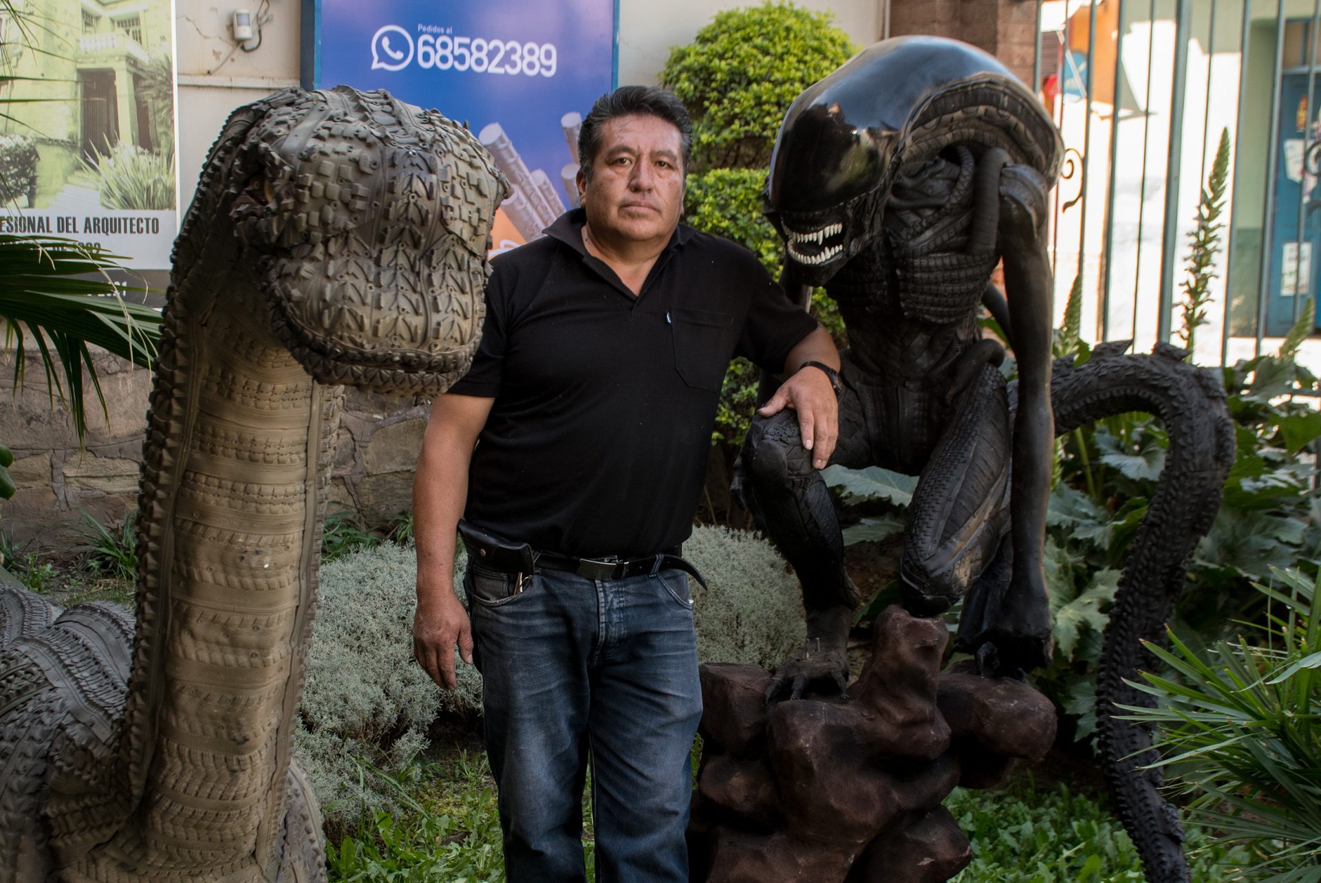 El artista plástico Sandro Arellano (c) posa, el pasado 1 de junio, junto a una de sus esculturas hecha de neumáticos descartados, en Cochabamba (Bolivia). EFE/Jorge Ábrego