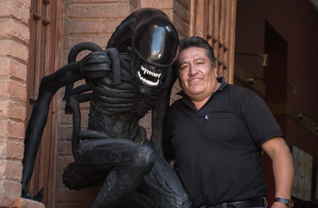 El artista plástico Sandro Arellano (c) posa, el pasado 1 de junio, junto a una de sus esculturas hecha de neumáticos descartados, en Cochabamba (Bolivia), con lo que busca crear conciencia ambiental. EFE/Jorge Ábrego