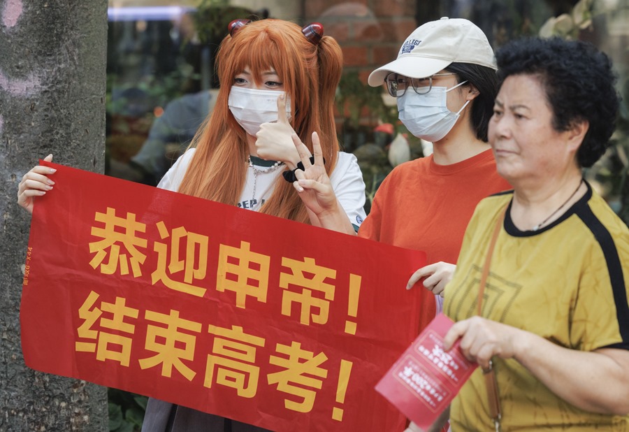 Familiares y amigos sostienen una pancarta que dice '¡Felicitaciones al emperador Shen! ¡Por terminar el examen de ingreso a la universidad!' mientras esperan a un estudiante que participa en el examen anual de ingreso a la universidad nacional de China, en una escuela en Shanghái, China. 