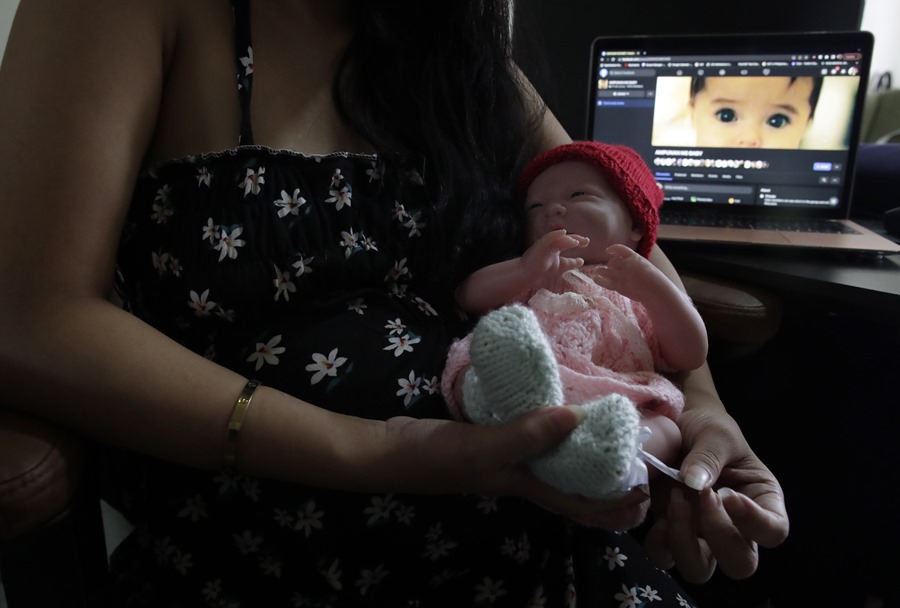 Melissa (nombre ficticio), una filipina embarazada de 21 años que ha decidido dar en adopción a su futuro bebé en el mercado ilegal de adopciones, sostiene una muñeca junto a un ordenador que muestra una página de Facebook utilizada para ese trámite.