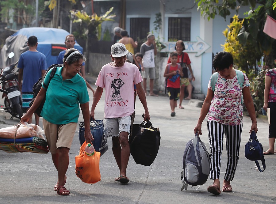 Filipinos que viven al pie del volcán Mayon llevan sus pertenencias durante una evacuación masiva en la ciudad de Daraga, provincia de Albay, Filipinas.