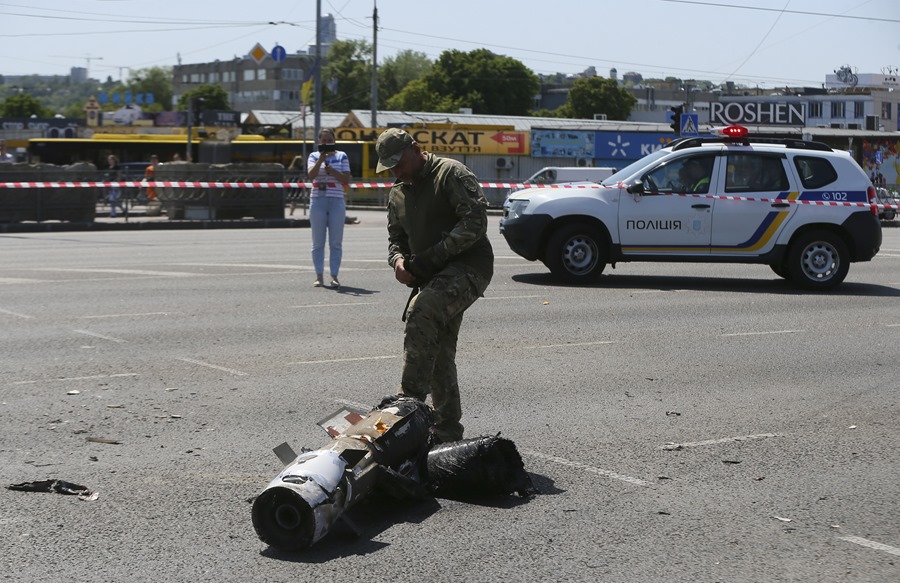 Un policía inspecciona los restos de un cohete en una calle de Kiev.