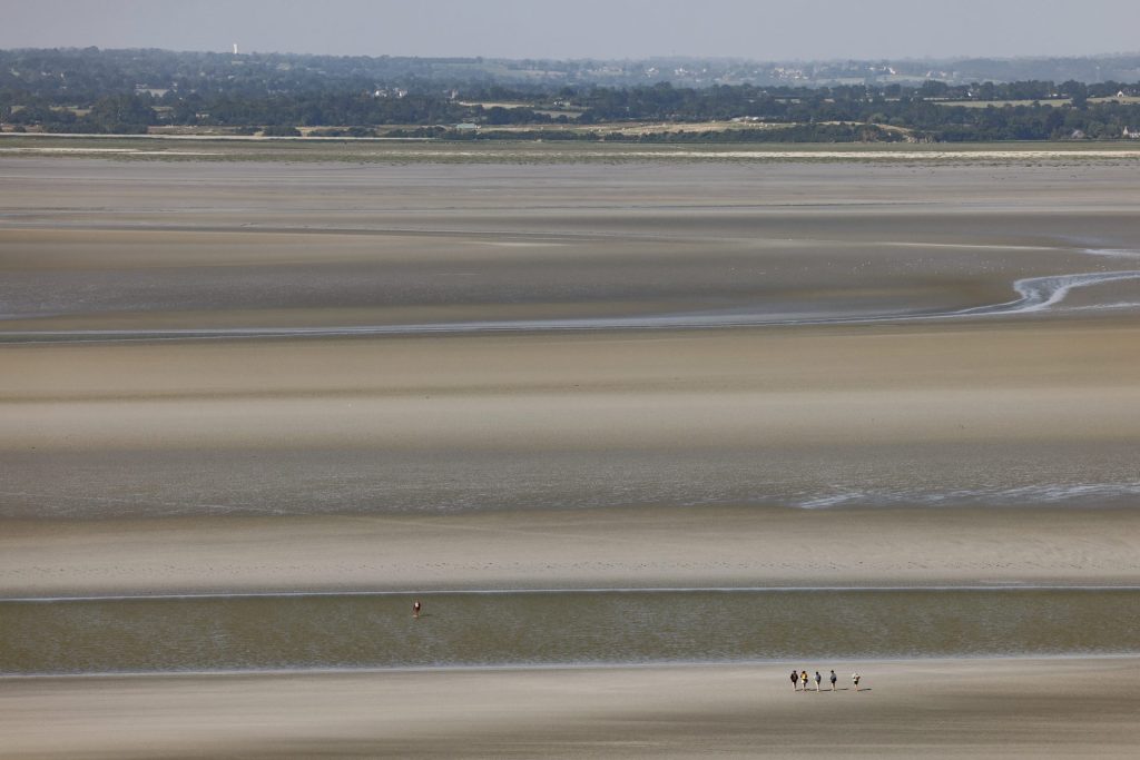 Turistas caminan por las playas de "Le Couesnon" en la bahía de Mont Saint-Michel, este 5 de junio de 2023. EFE/Ludovic Marin