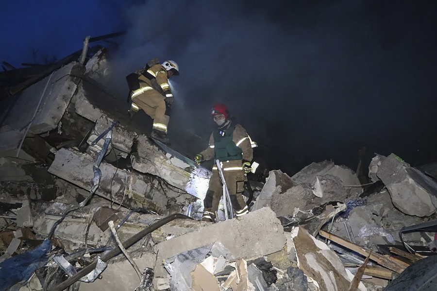 Foto proporcionada por el Servicio Estatal de Emergencia de Ucrania de varios rescatistas entre los escombros del edificio alcanzado el sábado por un cohete en el área de Dnipro, en el centro de Ucrania. 