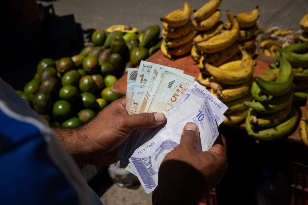 Fotografía de archivo que muestra a un vendedor informal que cuenta billetes de bolívar en el mercado de Quinta Crespo en Caracas (Venezuela), donde los clientes tratan de hacer que sus salarios rindan. EFE/Rayner Peña R.