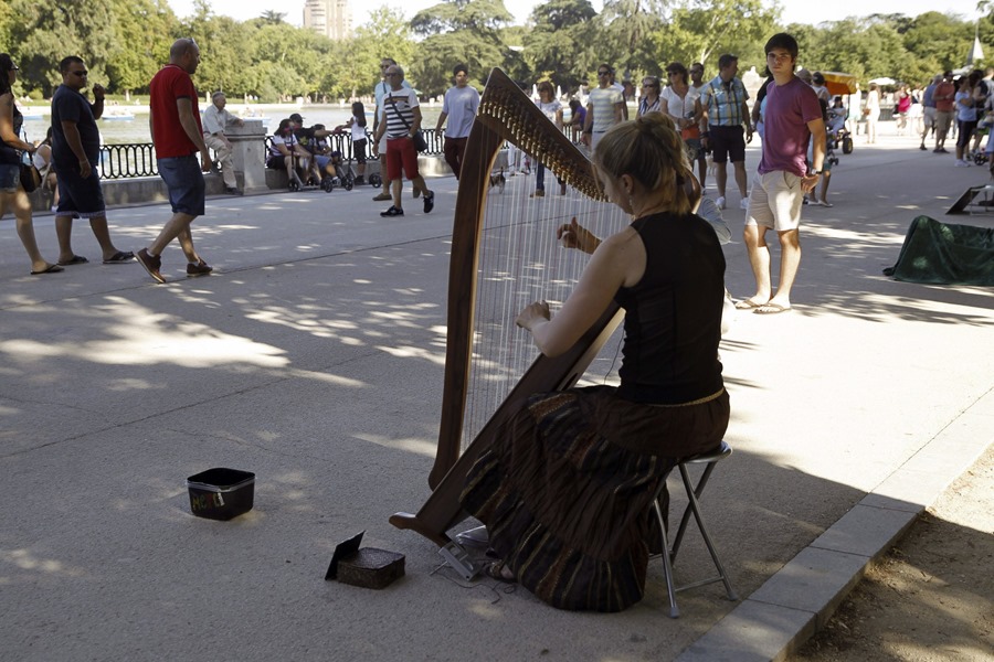Una mujer toca el arpa frente al lago del Retiro, con motivo de la celebración del Día Europeo de la Música.