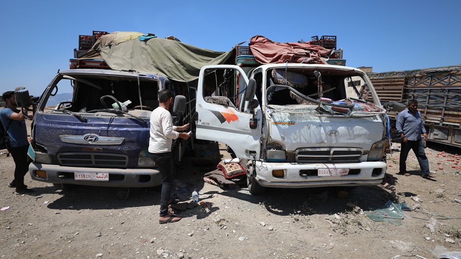 Las personas se paran junto a los camiones dañados en un mercado de verduras tras uno de los ataques