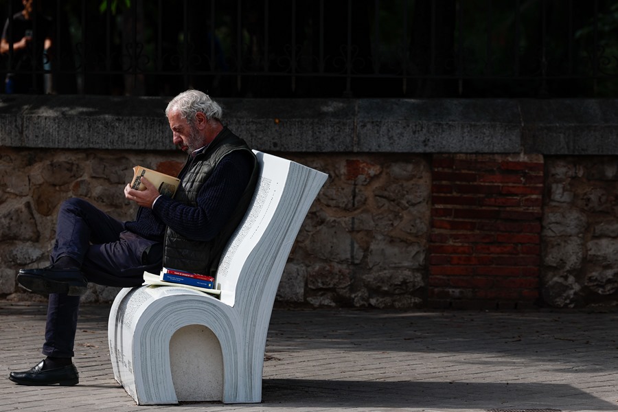 Una persona lee un libro en un banco