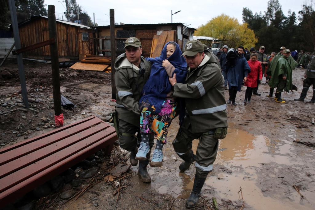Personal de Carabineros ayuda en la evacuación de habitantes debido a la creciente del río Clarillo, en la comuna de Pirque, producto de las intensas lluvias, en Santiago (Chile). EFE/Elvis González
