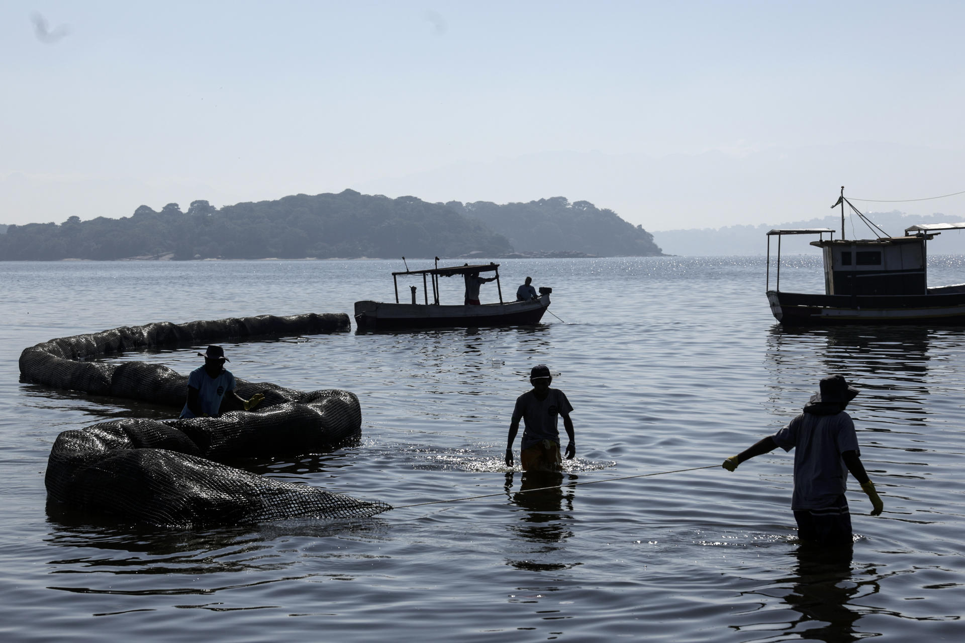 Fotografía que muestra hombres mientras trabajan en una barrera de contención de 200 metros de extensión hoy, en una playa de la bahía de Guanabara en Río de Janeiro (Brasil). EFE/Antonio Lacerda