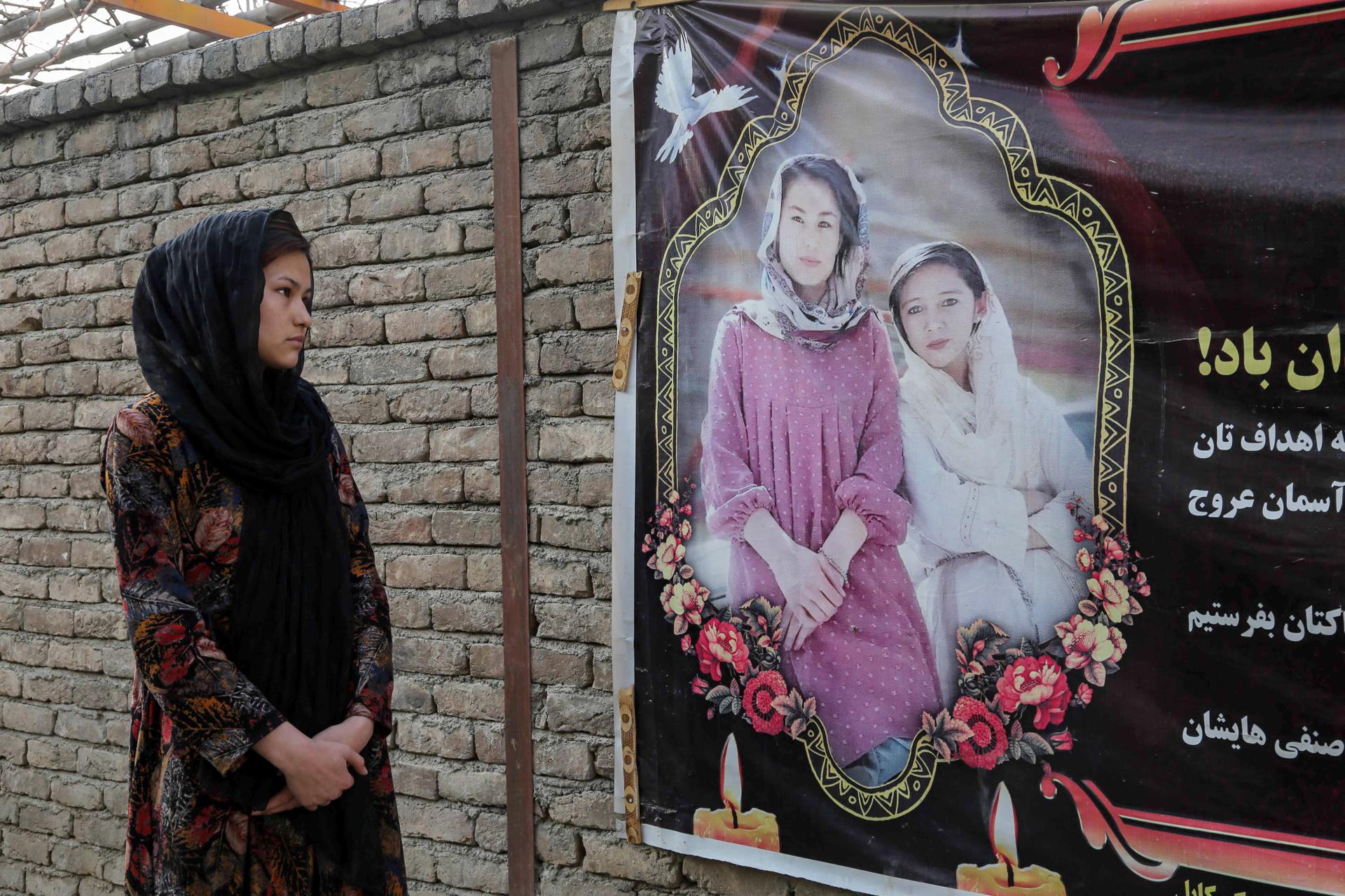 Zahra Mohammadi, the elder sister of deceased Marzia, stands beside a poster reading in Dari 'Marzia and Hajar, martyrs of knowledge, may your souls be happy and may your memories live forever' outside of their house in Kabul, Afghanistan, 22 March 2023 (issued 24 March 2023). EFE-EPA/SAMIULLAH POPAL