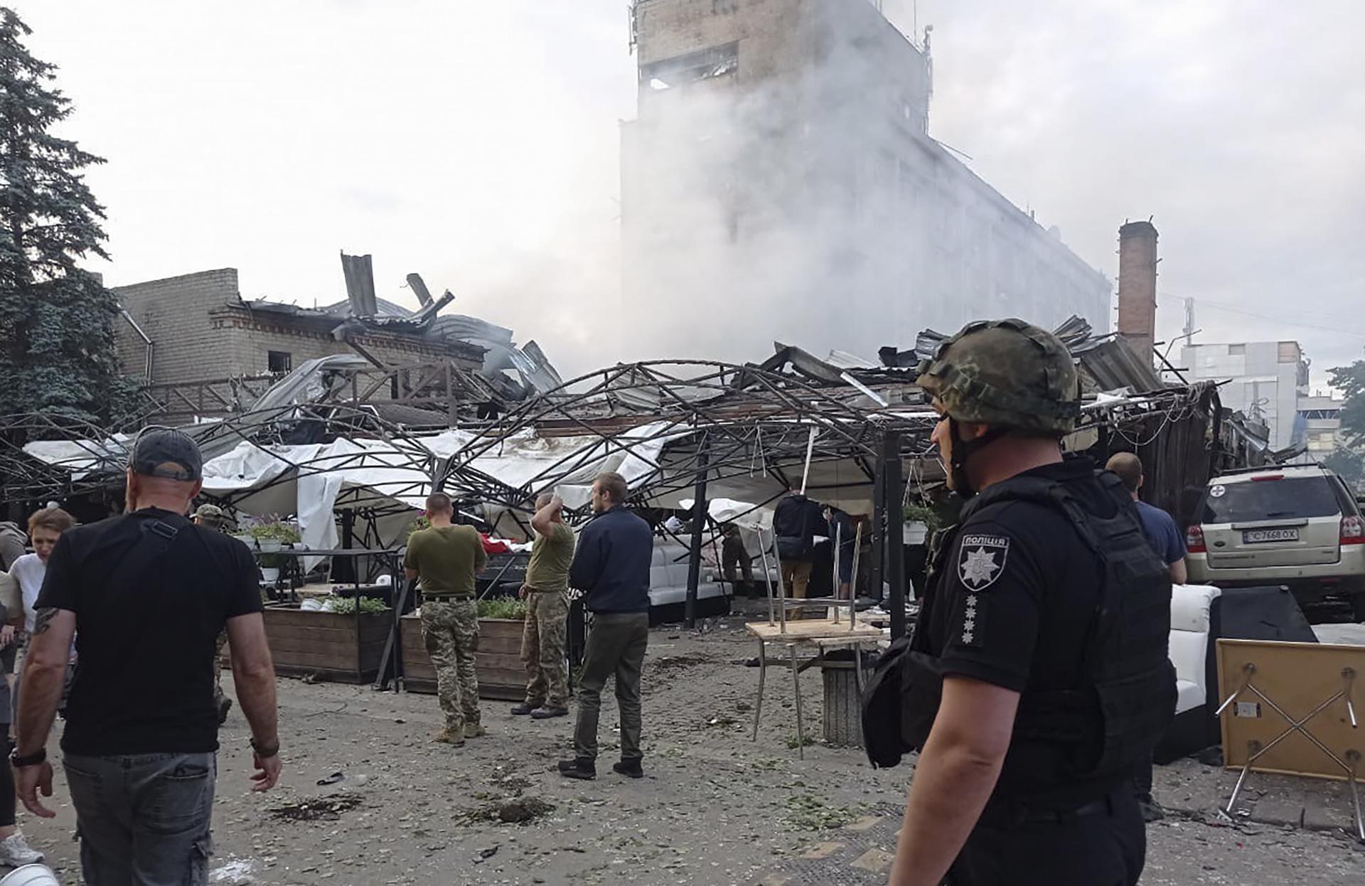 Varias personas observan los daños caudos por un ataque ruso con misiles contra una concurrida zona comercial y de restaurantes de la ciudad de Kramatorsk, en el este de Ucrania,