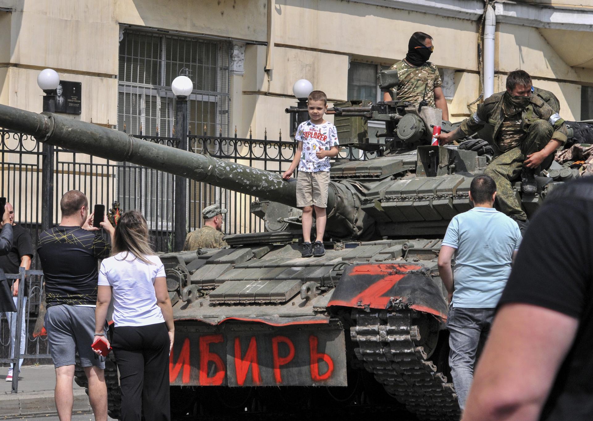 A child poses for a photo on a tank reading 'Siberia' as servicemen from private military company (PMC) Wagner Group block a street in downtown Rostov-on-Don, southern Russia, 24 June 2023. EFE-EPA/ARKADY BUDNITSKY
