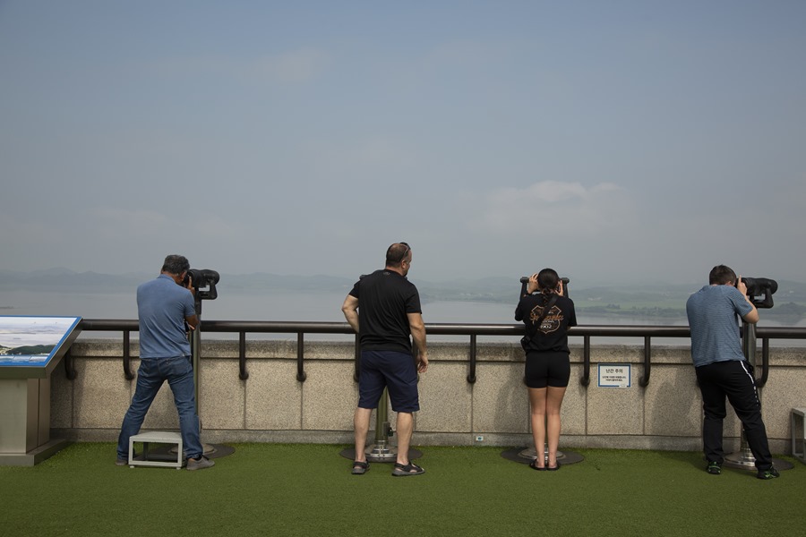 Turistas extranjeros observan con binoculares el lado norcoreano de la frontera desde el observatorio Odusan cerca de la Zona Desmilitarizada en Paju, Corea del Sur. 