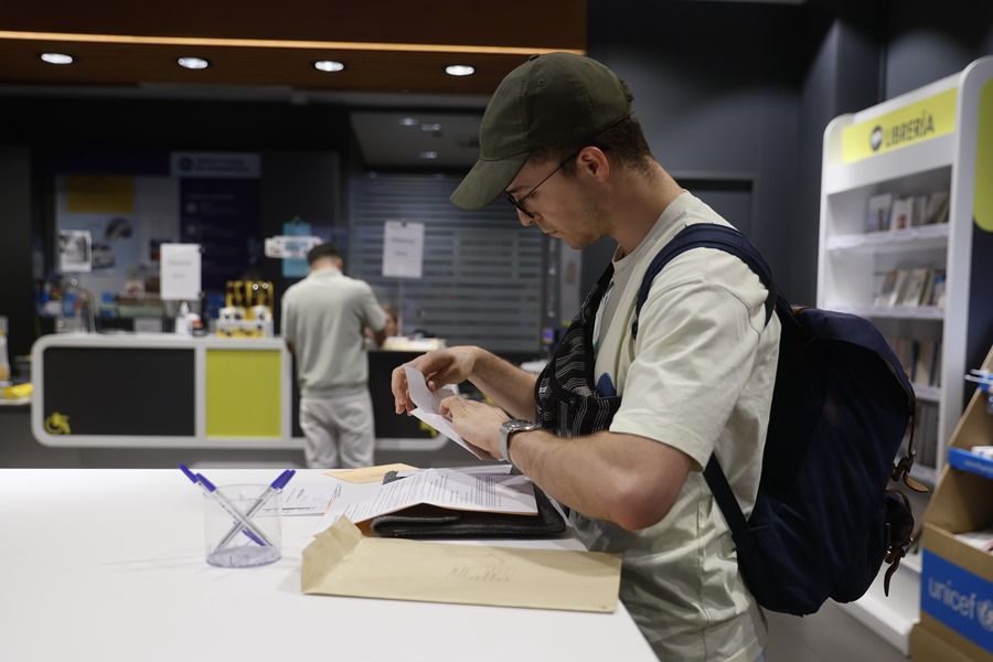 Un hombre cumplimenta la documentación para ejercer el voto por correo en una oficina de Madrid.