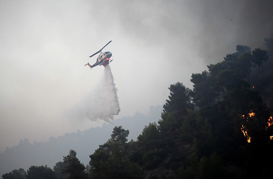 Un helicóptero arroja agua para extinguir un incendio forestal, en Diakopto, Egio, Grecia.