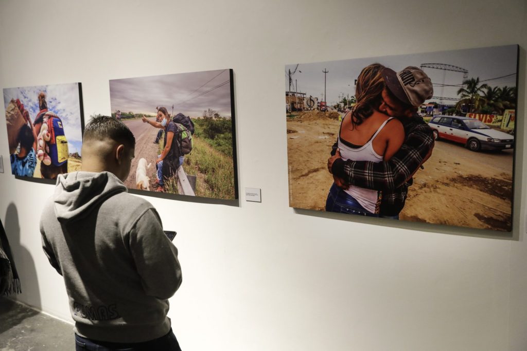 Un hombre revisa su celular mientras observa fotografías de la exposición "Del Otro Lado", el 6 de julio de 2023, en Bogotá (Colombia), que muestra las complejidades de la migración. EFE/Carlos Ortega