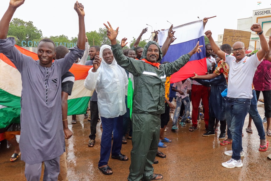 Partidarios del golpe de Estado en Níger sostienen banderas de su país y de Rusia, frente al edificio de la Asamblea Nacional en Niamey