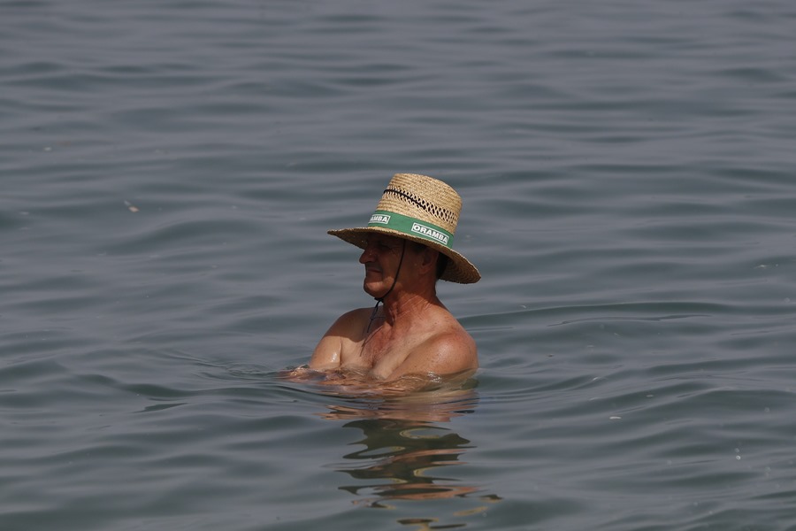 Un hombre con sombrero dentro del agua de la playa de la Malagueta en Málaga.