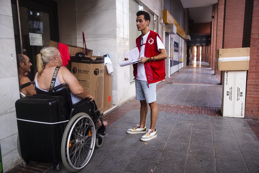 El trabajador social de Cruz Roja Miguel Ángel Cruz, de la unidad de Emergencia Social, atiende a varias personas sin hogar en el centro de la ciudad de Málaga.