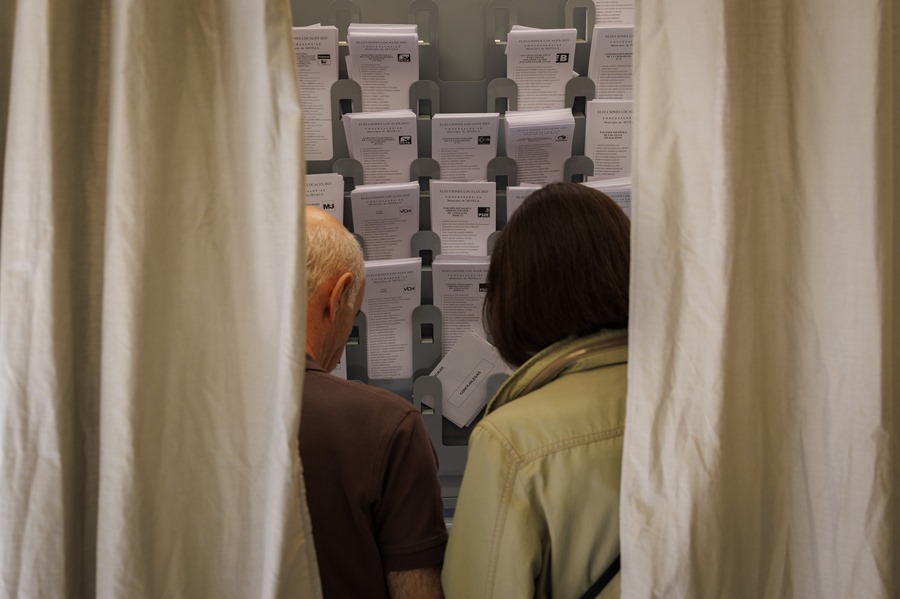 Dos personas eligen papeleta para ejercer su derecho al voto