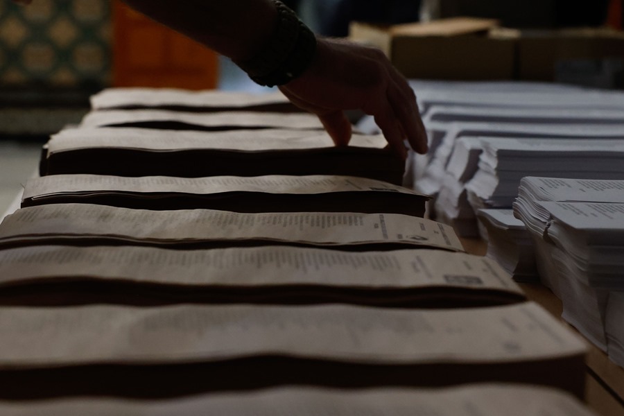 Un hombre escoge entre las papeletas para votar en un colegio electoral.