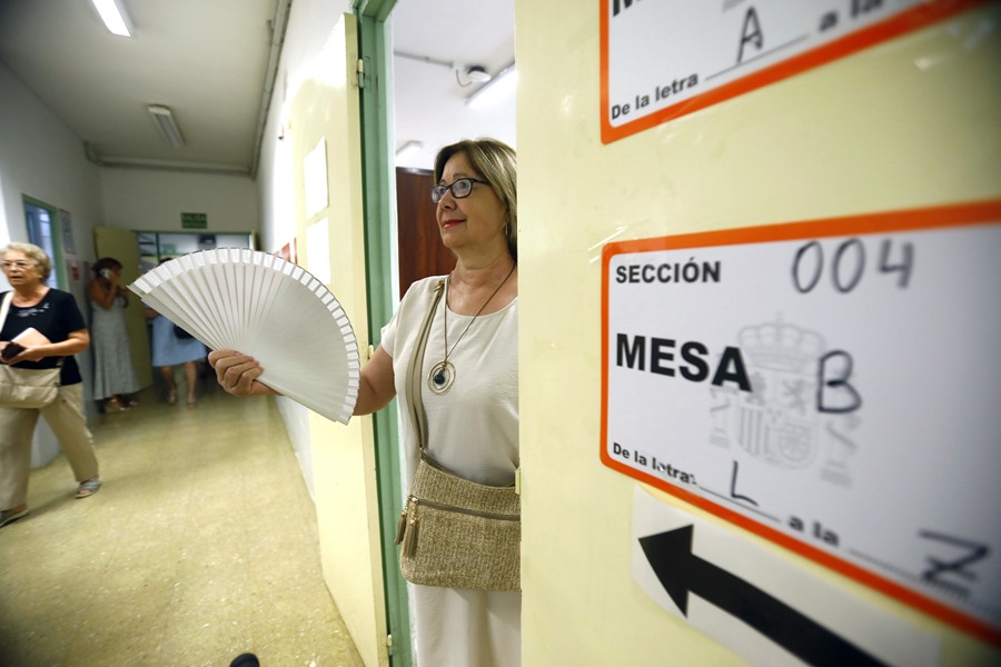 Una mujer con abanico sale tras ejercer su derecho al voto en el Colegio Miguel de Cervantes de Écija (Sevilla)