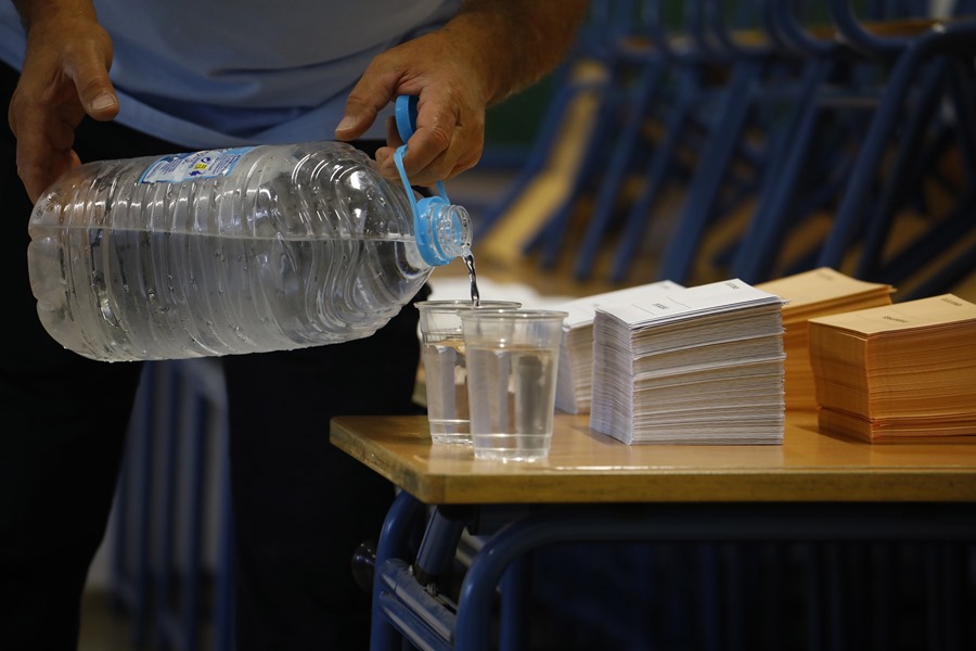 Un hombre llena vasos de agua en el colegio electoral en la Casa de la Juventud en Écija (Sevilla), este domingo 23J de elecciones generales. 