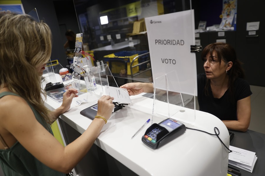 Una mujer entrega la documentación para ejercer el voto por correo en una oficina de Madrid.