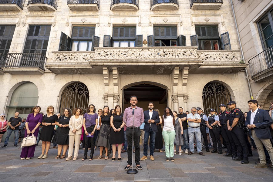 Decenas de ciudadanos se concentraron este mediodía frente al edificio del Ayuntamiento de Girona, en un acto encabezado por el alcalde de la ciudad, Lluc Salellas (c), contra el asesinato de una joven de 26 años.