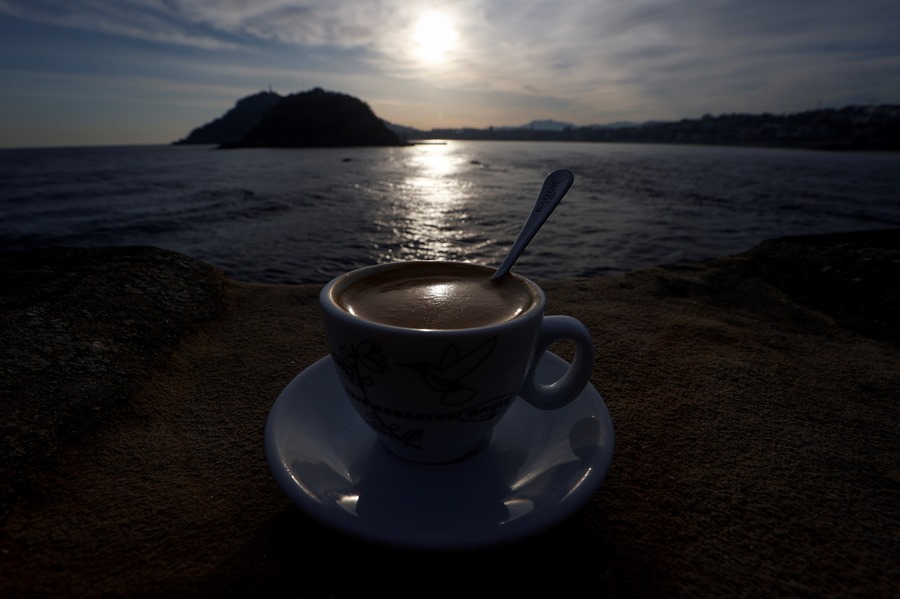 Una persona toma un café junto a la playa de Ondarreta de San Sebastián