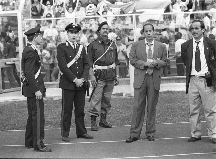 El entonces seleccionador de España Luis Suárez, acompañado por el Delegado de la FIFA y por los "Carabinieris", abandona el campo tras ser explusado en una partido en 1990