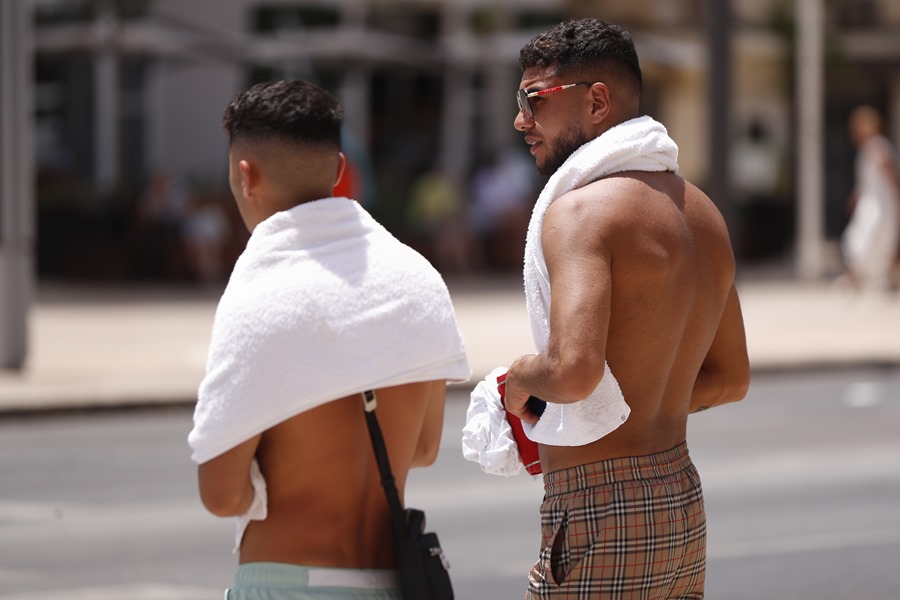 Varios jóvenes caminan por el centro de Málaga con toallas al cuello