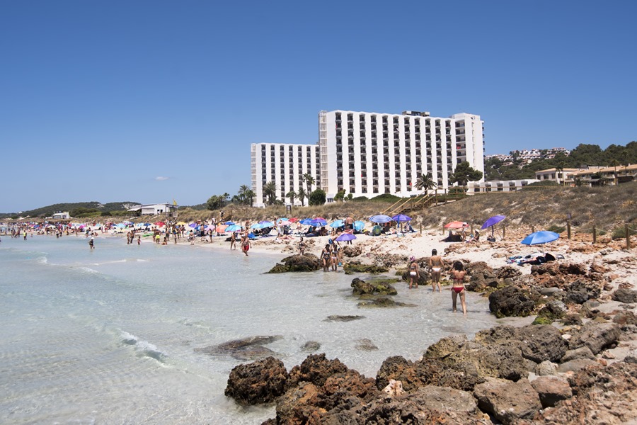 Varias personas disfrutan de la playa de frente al hotel Meliá Sol Son Bou en Alayor, Menorca.