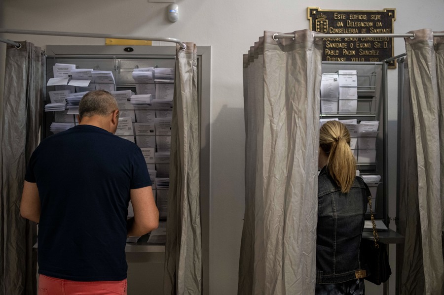 Dos personas escogen papeletas en un colegio electoral