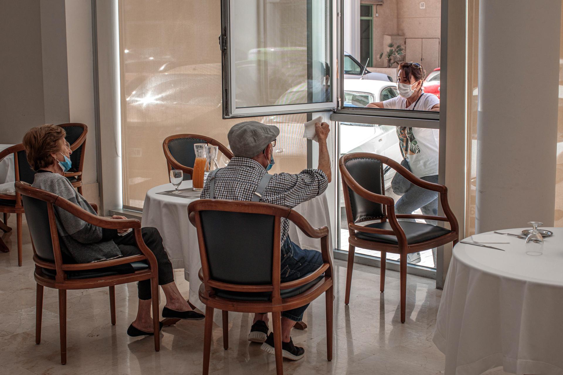 Una persona conversa con sus padres a través de una ventana habilitada en una residencia de mayores. Archivo/EFE/Biel Aliño