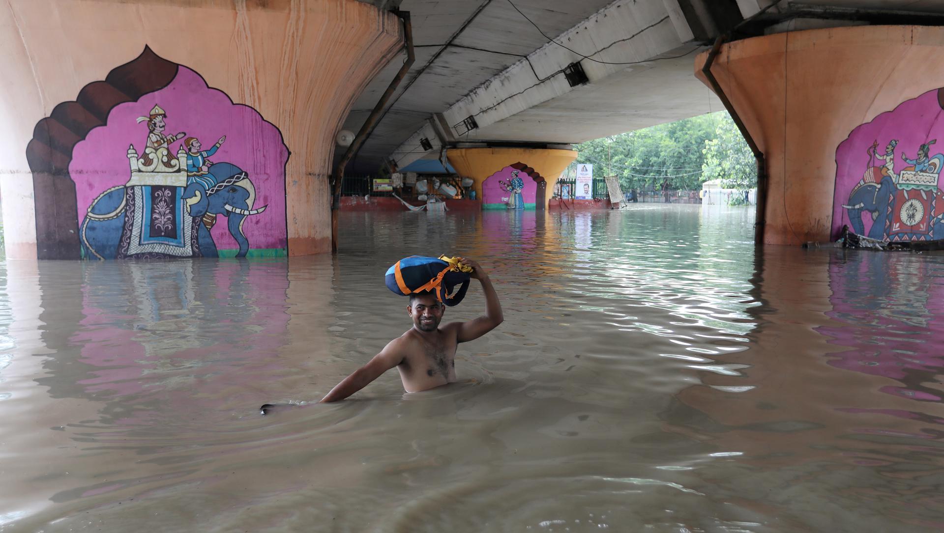 A man carries something on his head wading through floodwaters in New Delhi on 14 July 2023. EFE/EPA/RAJAT GUPTA
